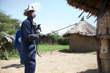 Man conducting indoor residual spraying of a rural African house