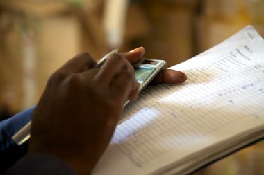 Picture of a hand entering numbers into a calculator while holding a document