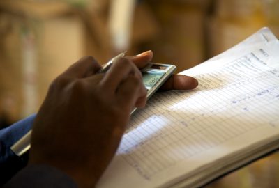 Picture of a hand entering numbers into a calculator while holding a document